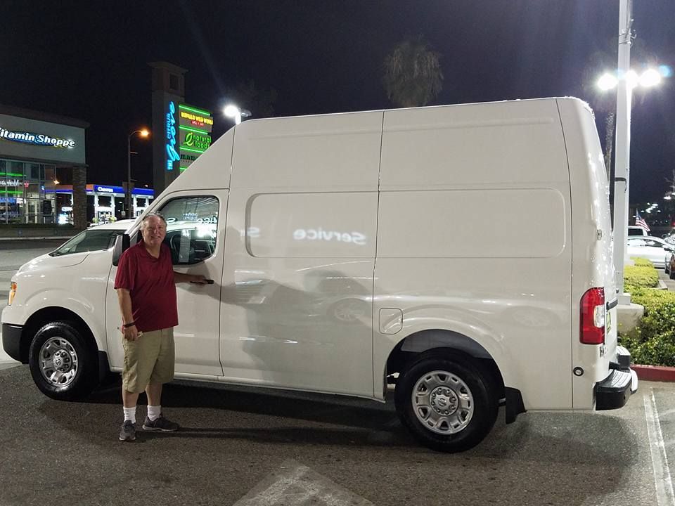 Person standing beside a white cargo van in a lit parking lot at night.