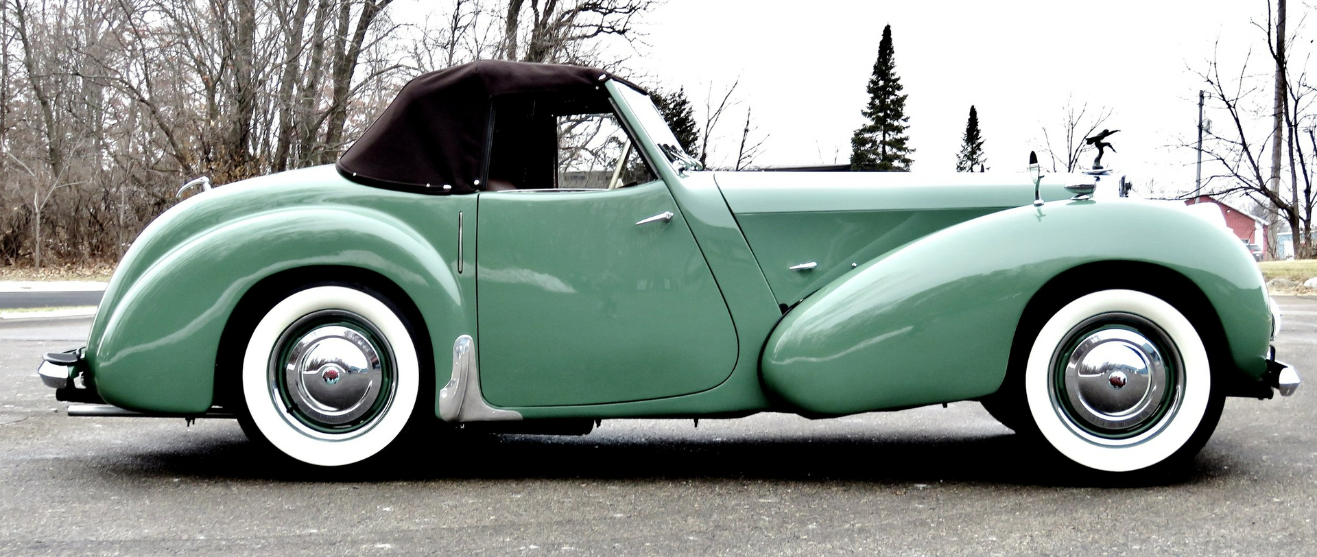 A green car with white tires is parked on the side of the road
