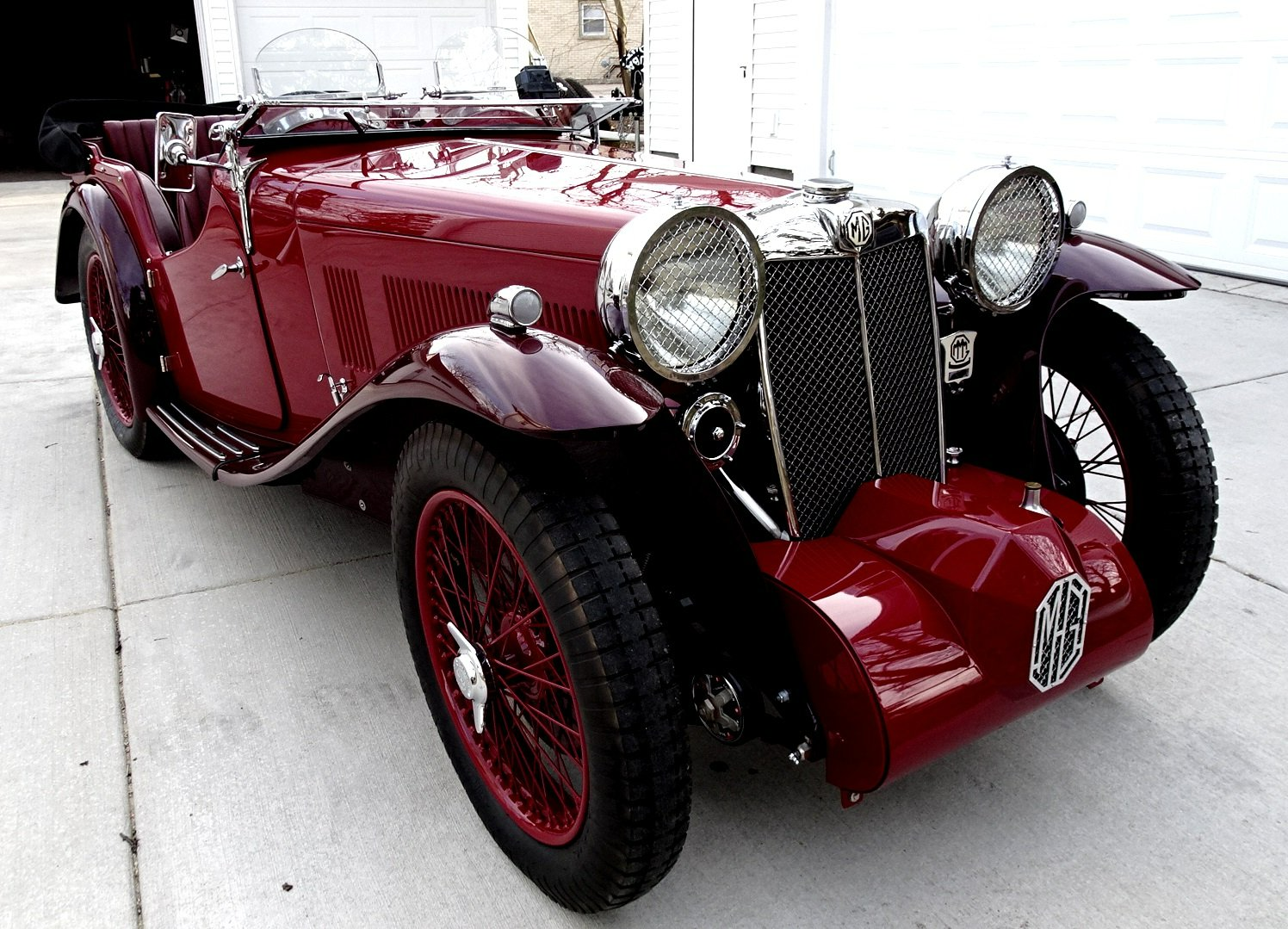 A red car with a mr logo on the front is parked on a sidewalk