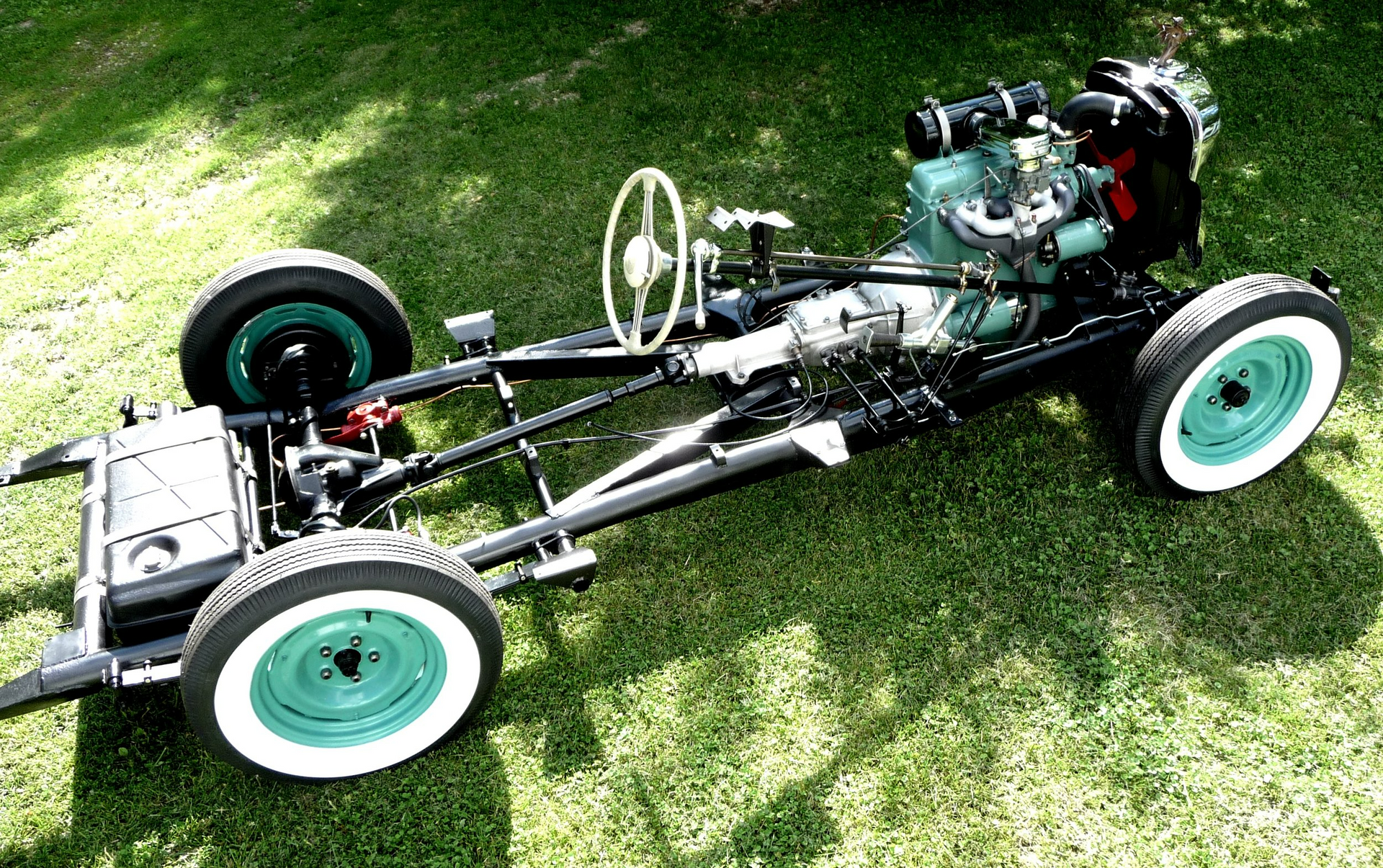 A car chassis is sitting on top of a lush green field.