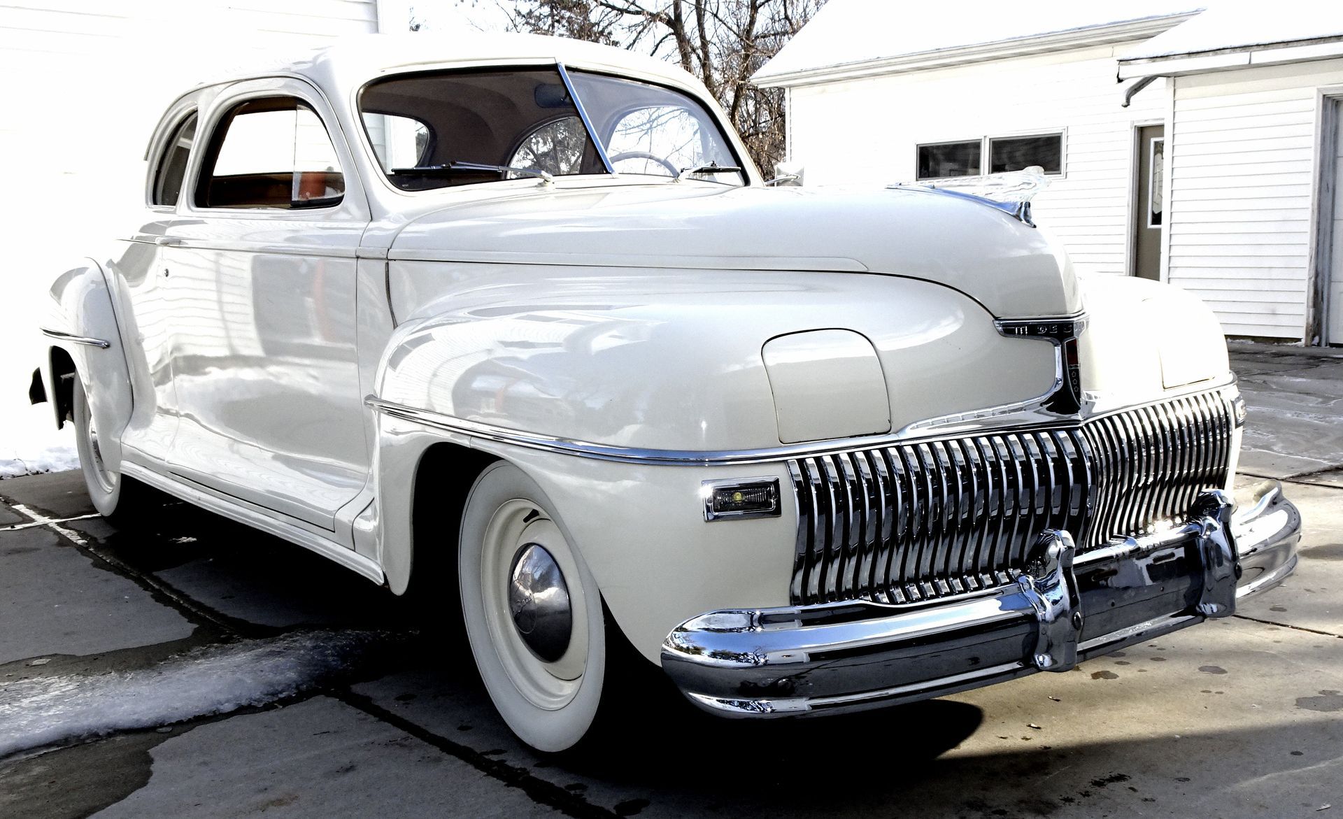 An old white car is parked on the side of the road