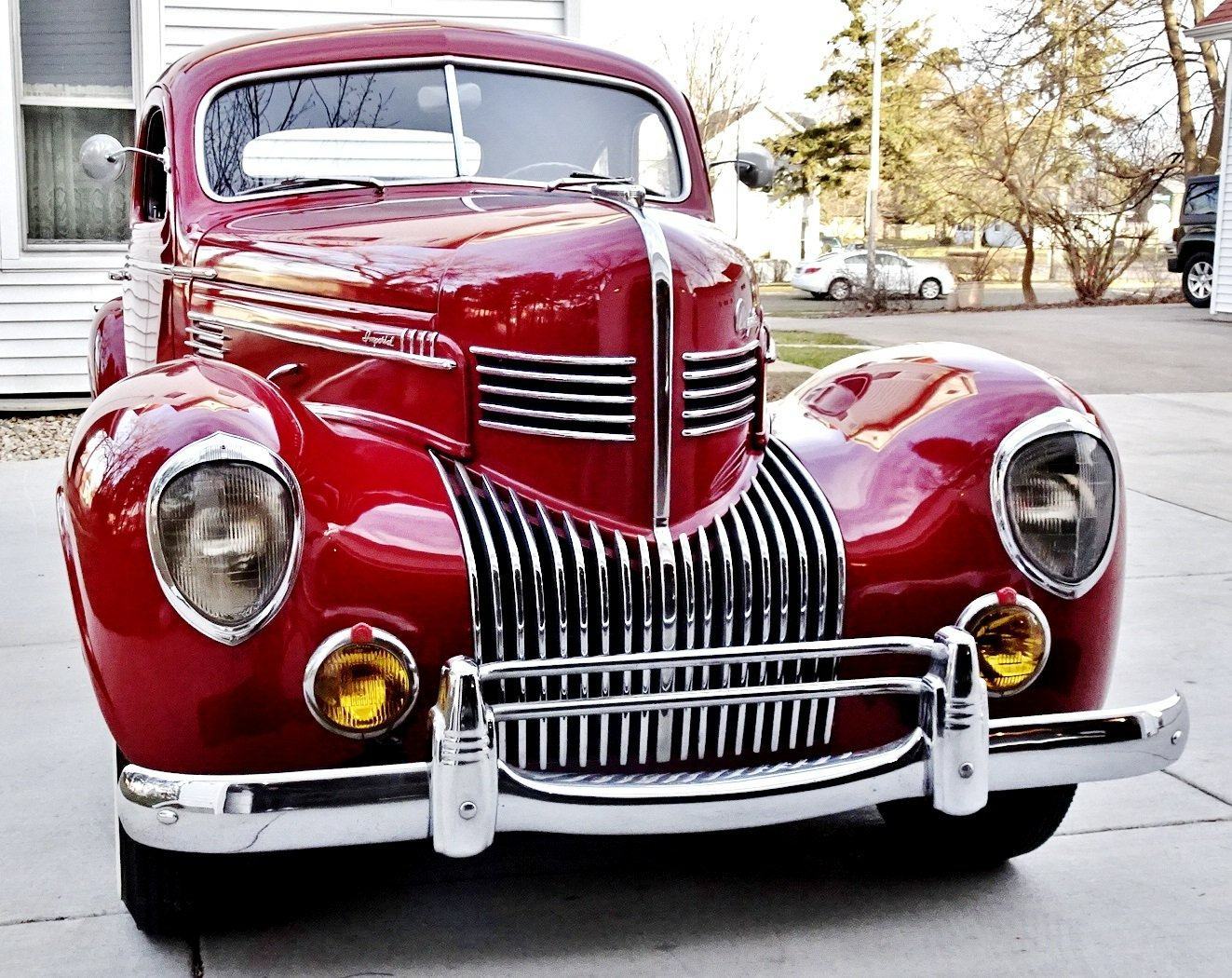 A red car is parked in a driveway in front of a house