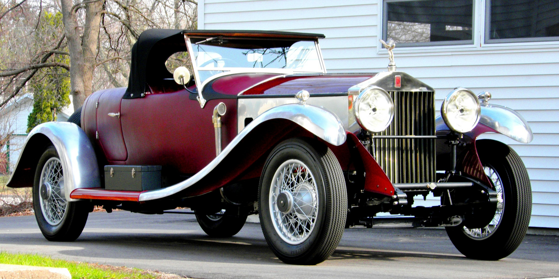 A red car is parked in front of a white house