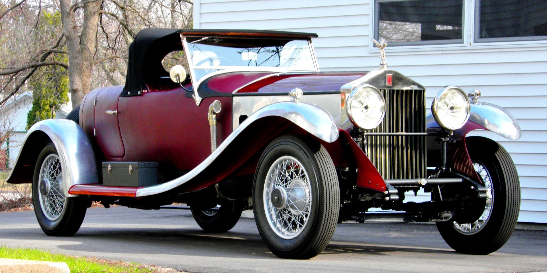 A red car is parked in front of a white house