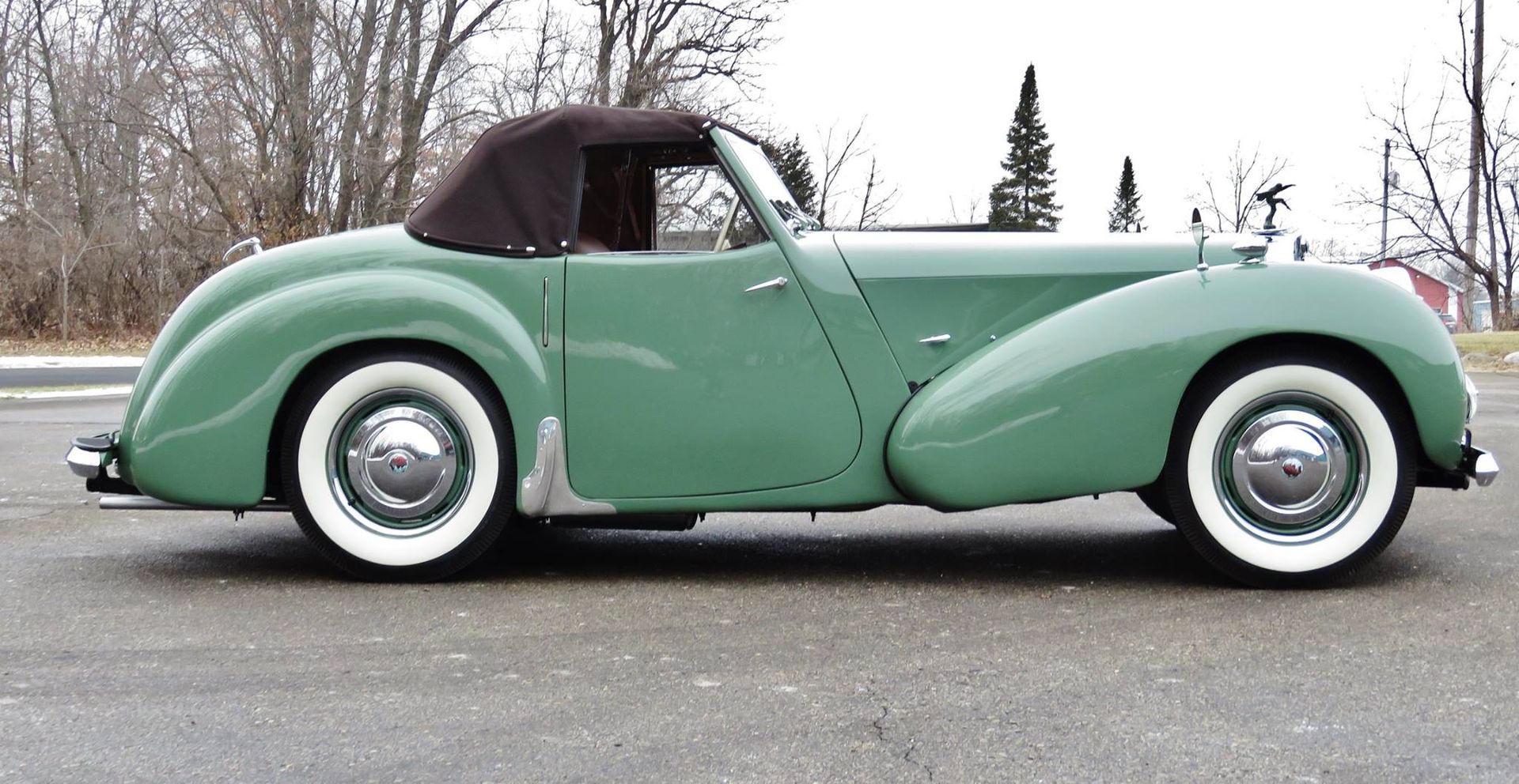 A green car with white tires is parked on the side of the road