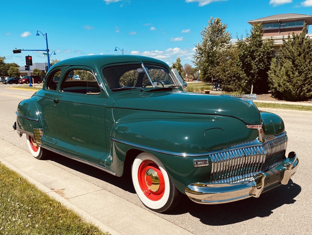A green car with white tires is parked on the side of the road.