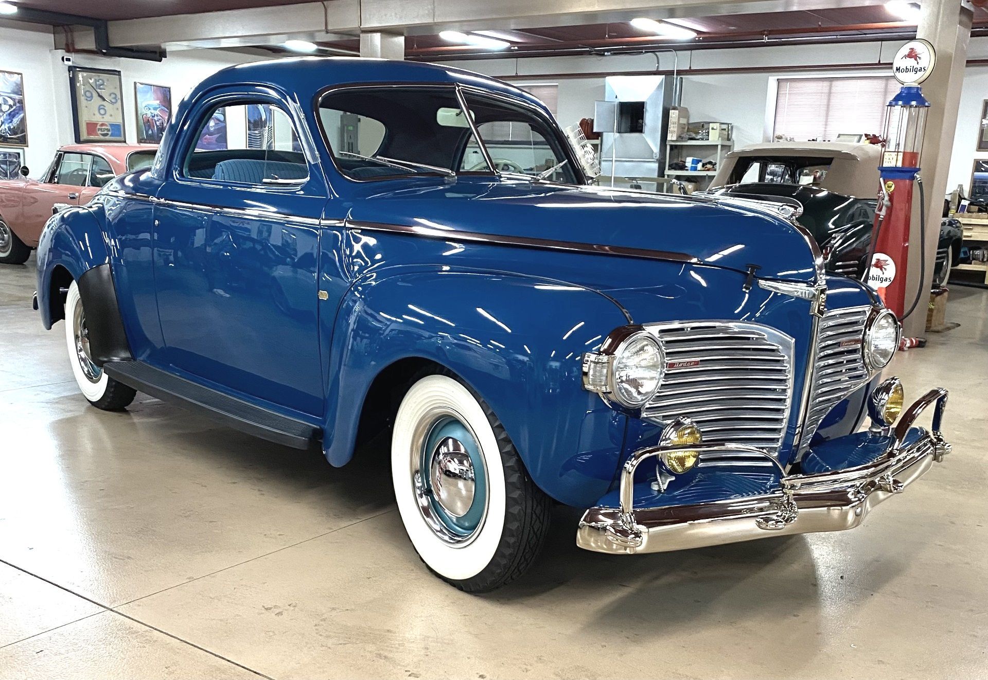 A blue car with white tires is parked in a garage