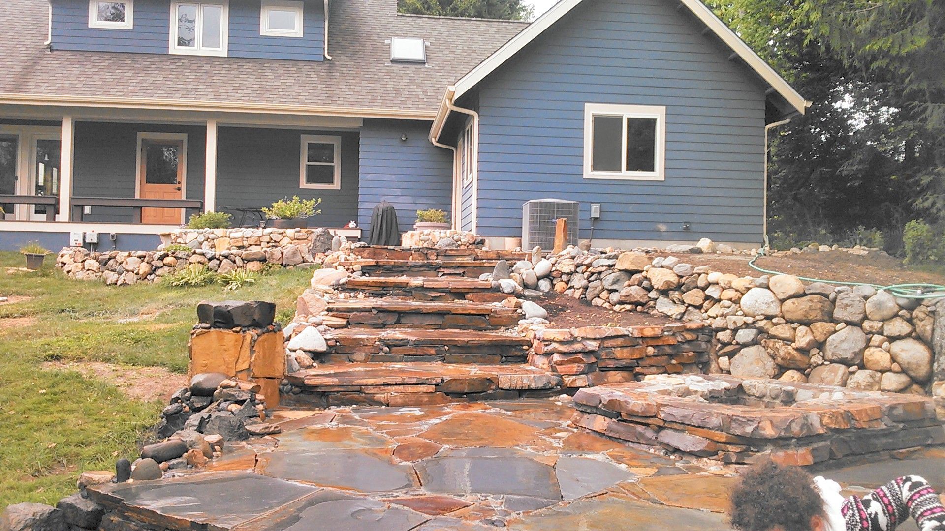 Stone blocks stacked to form a fire pit on a patio, with a retaining wall and wooden fence in the background.