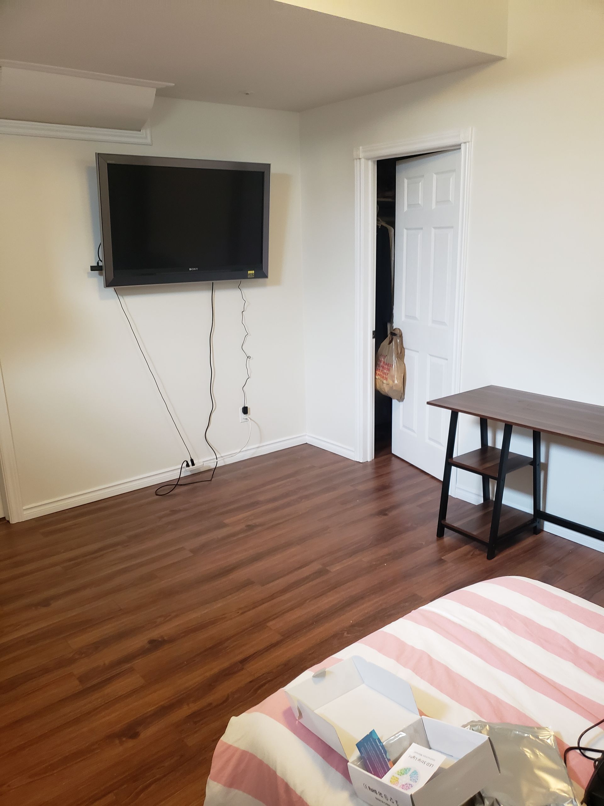 A bedroom with a bed and a flat screen tv on the wall.