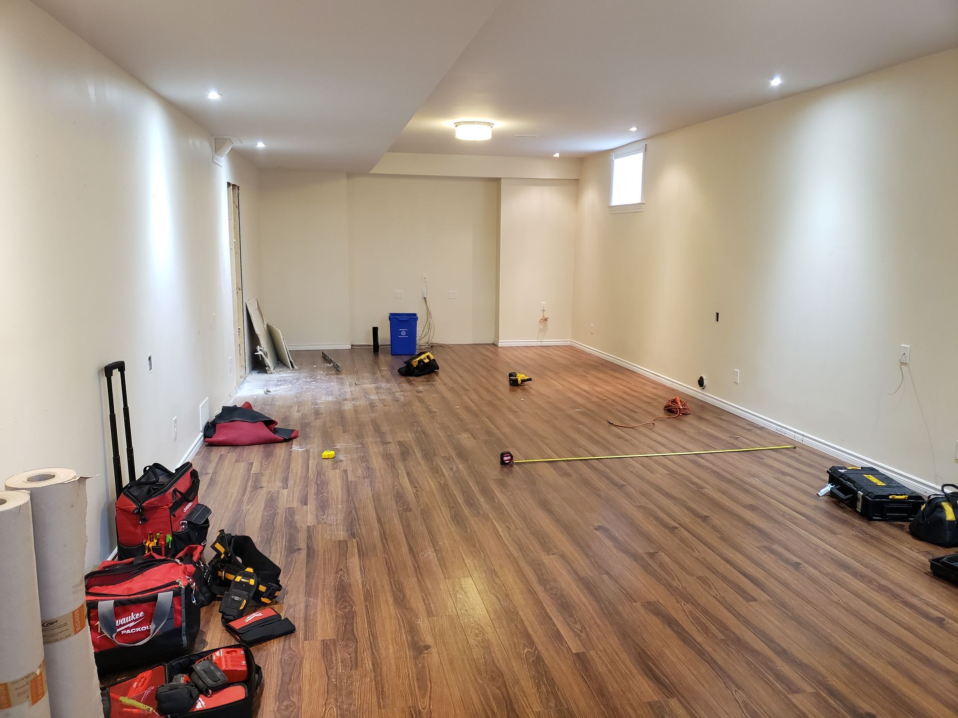 A large empty room with hardwood floors and tools on the floor.