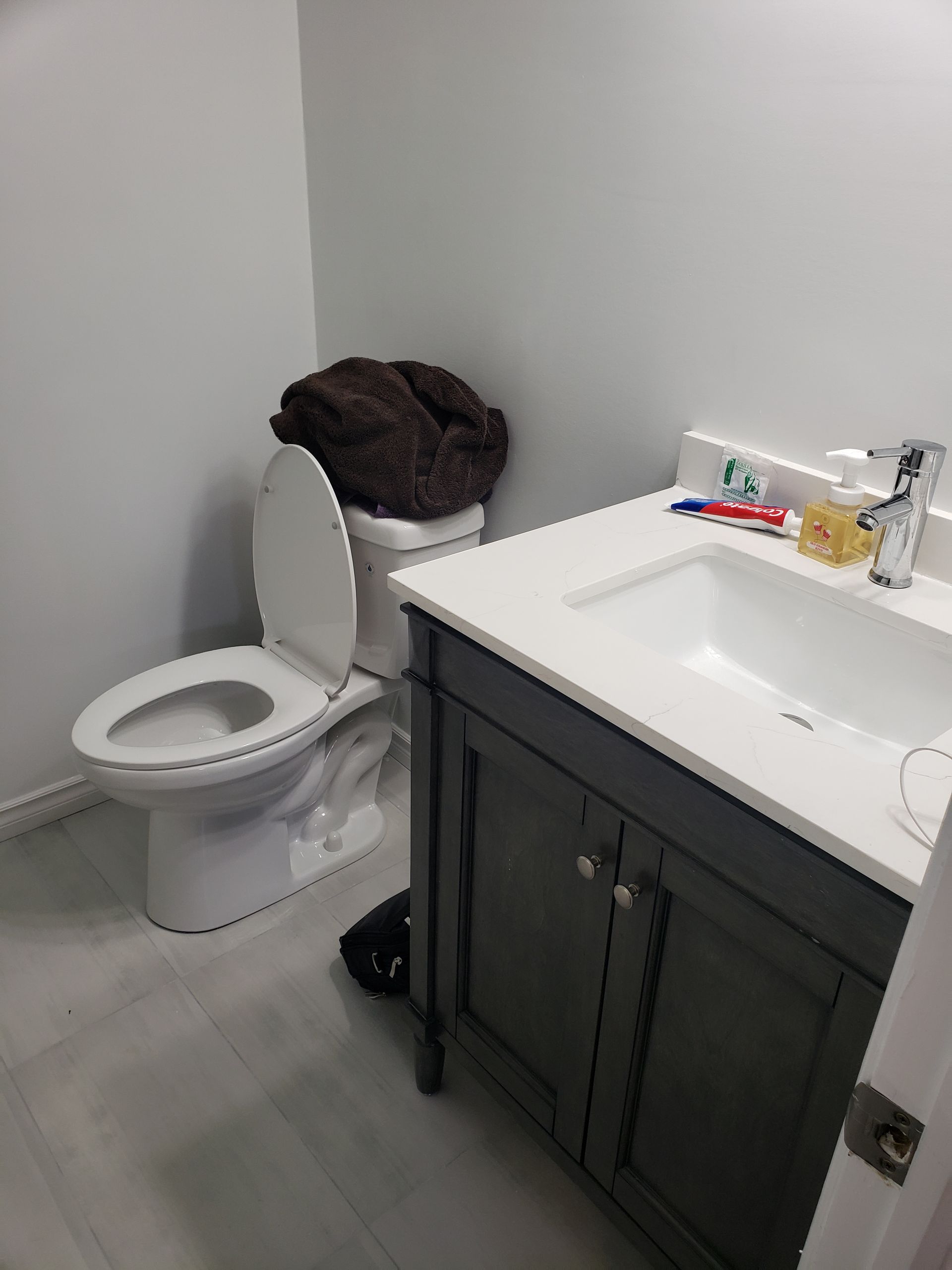 A bathroom with a toilet , sink , and cabinet.