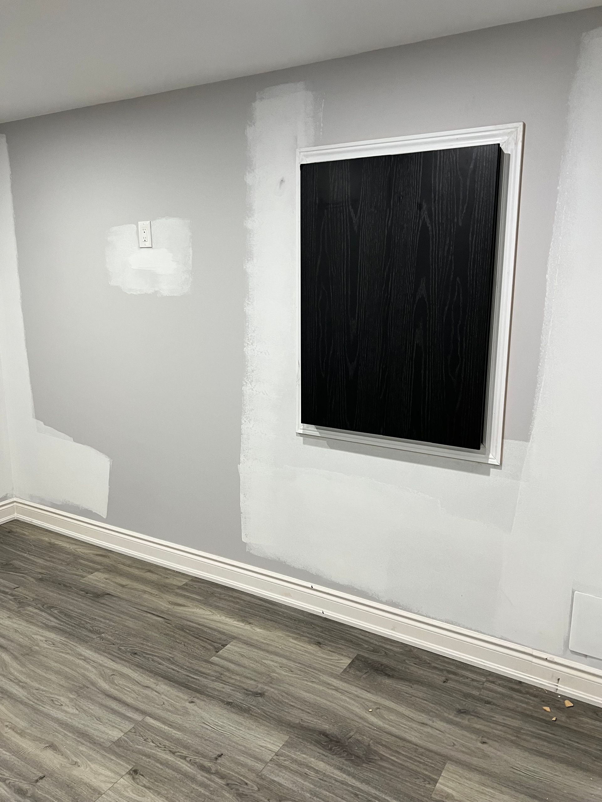 A room with a picture on the wall and a wooden floor.