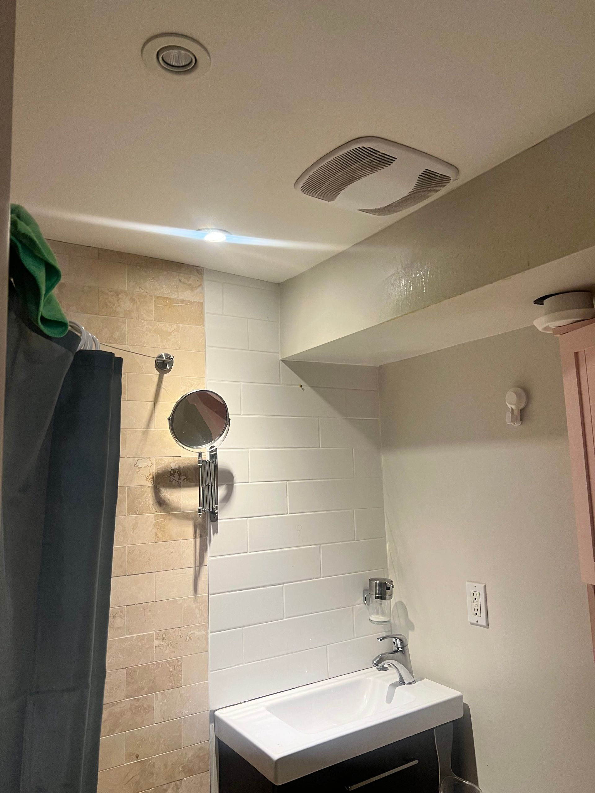 A bathroom with a sink , mirror and shower.