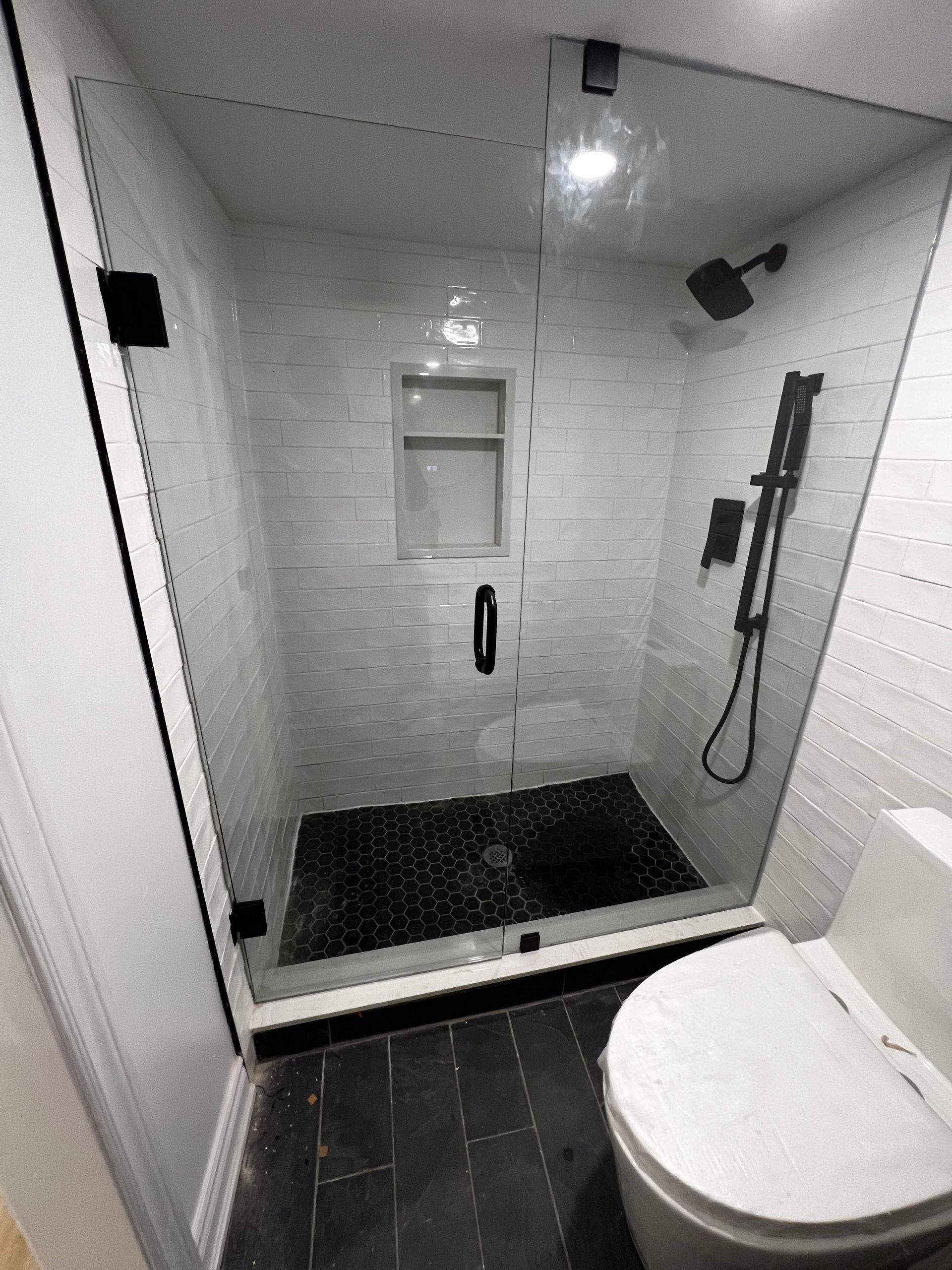 A bathroom with a toilet and a shower with a glass door.