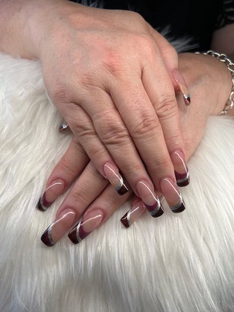 A woman 's hands with long nails are sitting on a white fur blanket.
