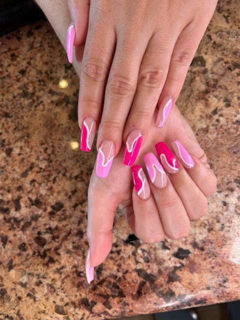 A woman 's nails are painted pink and white and are sitting on a counter.