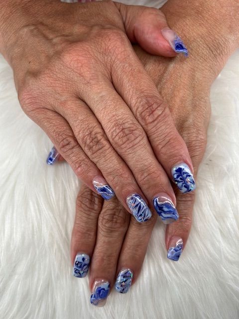 A close up of a woman 's hands with blue and white nails.