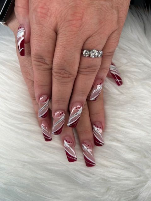 A woman 's hand with red and white nails and a ring on her finger.