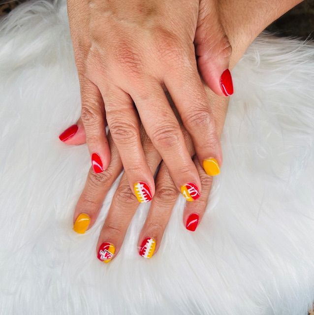 A close up of a woman 's hands with red and yellow nails