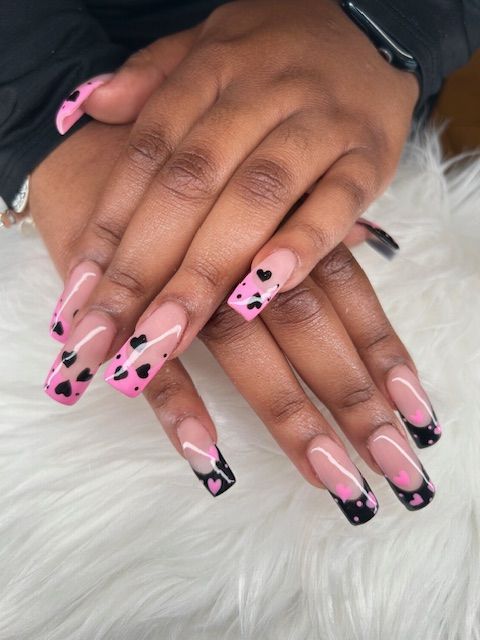 A woman 's nails are painted pink and black with hearts on them