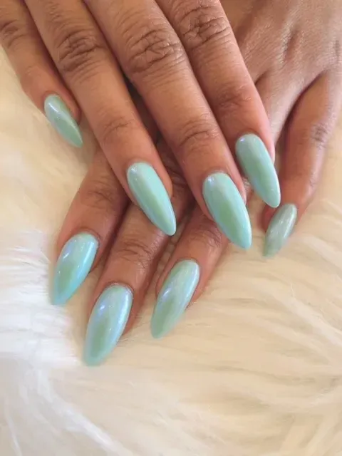 A close up of a woman 's hands with long light blue nails.