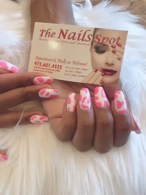 A woman is holding a business card for the nails spot