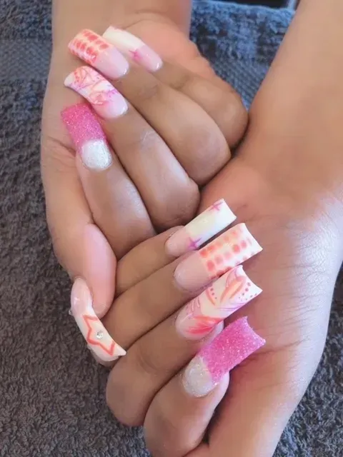 A woman 's hands with long pink and white nails
