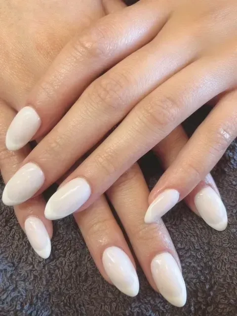 A close up of a woman 's hands with white nails