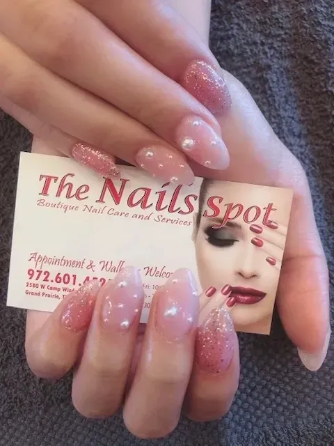 A woman holding a business card for the nails spot