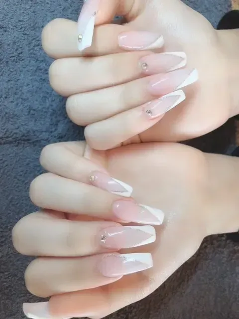 A woman 's hands with long pink and white nails