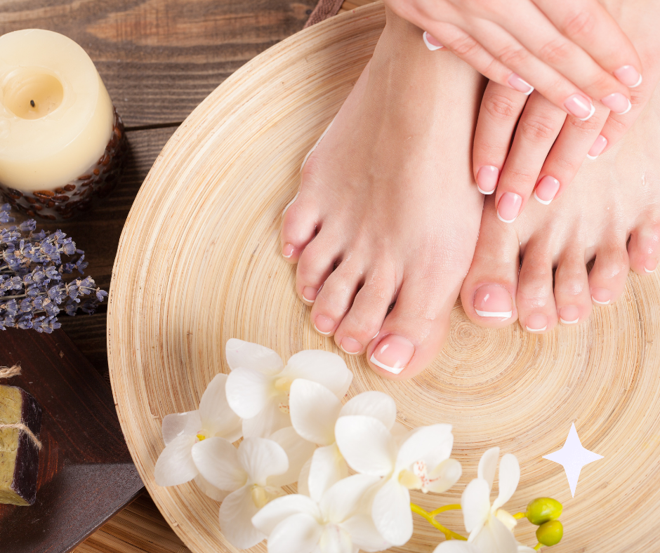 A woman 's feet are on a wooden plate next to flowers and candles.