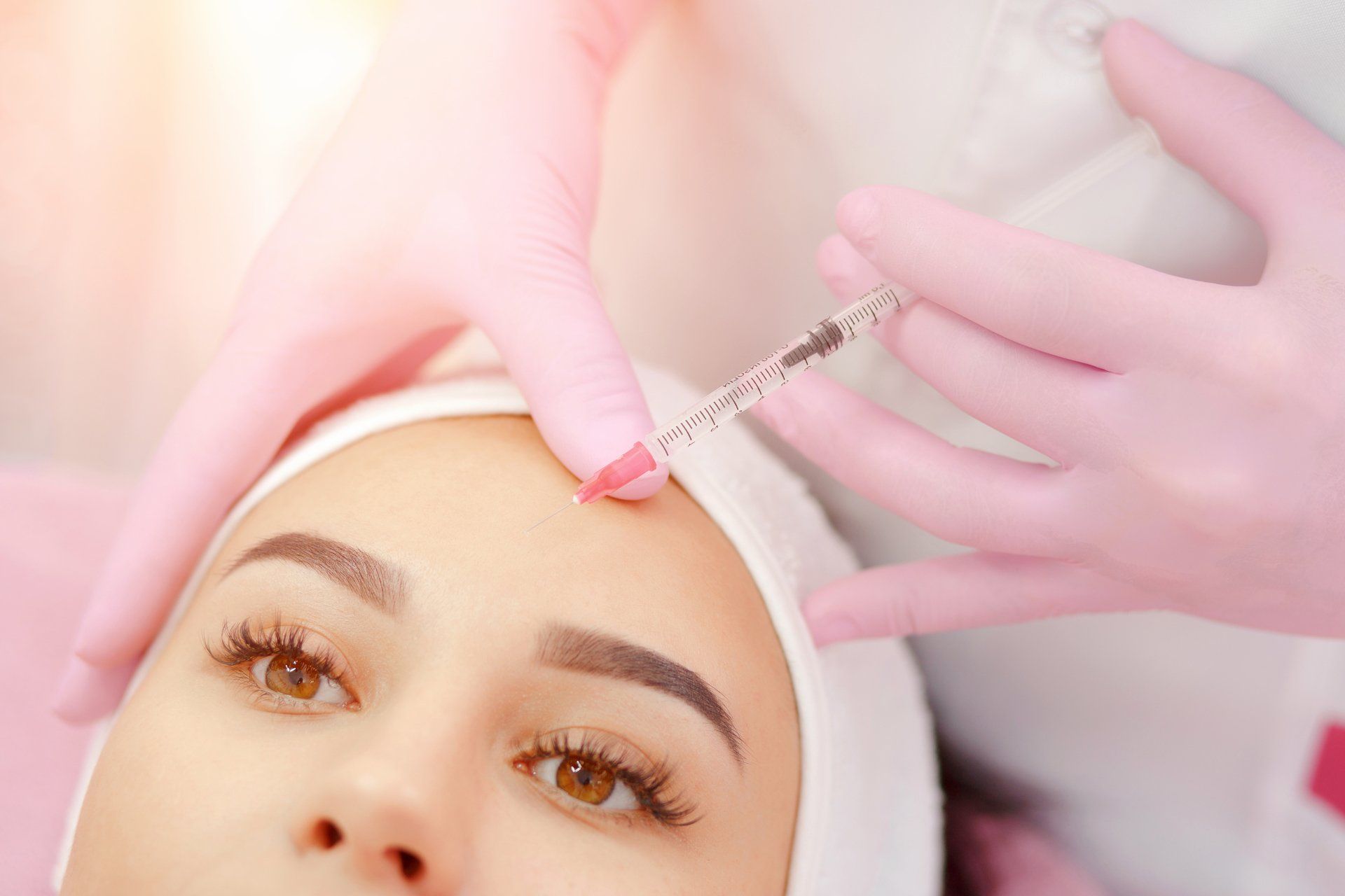Person receiving a Botox injection on their forehead in a beauty salon.
