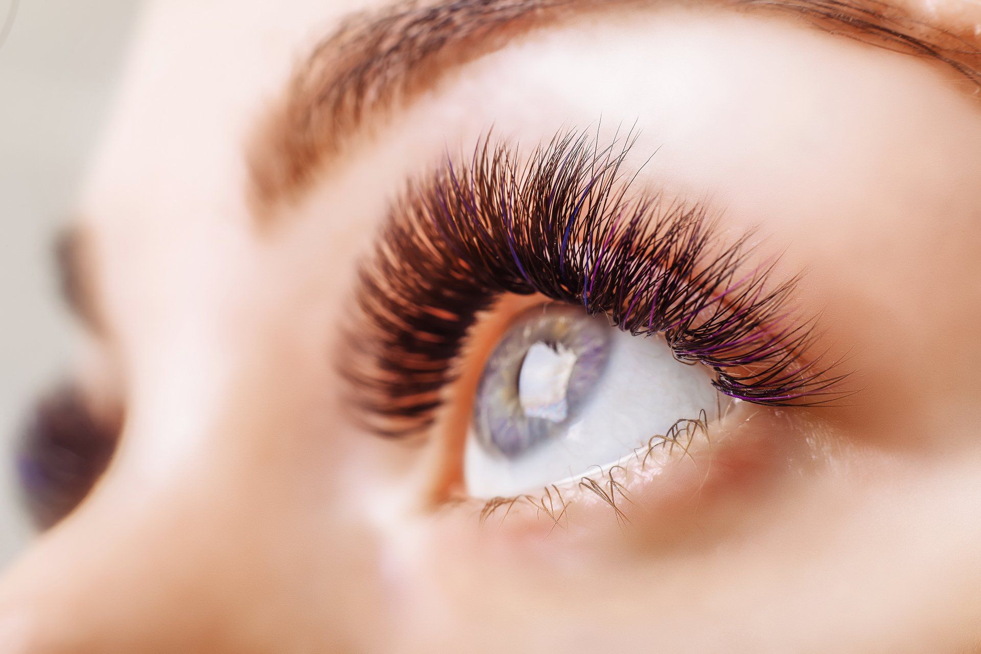 Close-up of eye with long, dark eyelashes and light-colored iris, looking upward.
