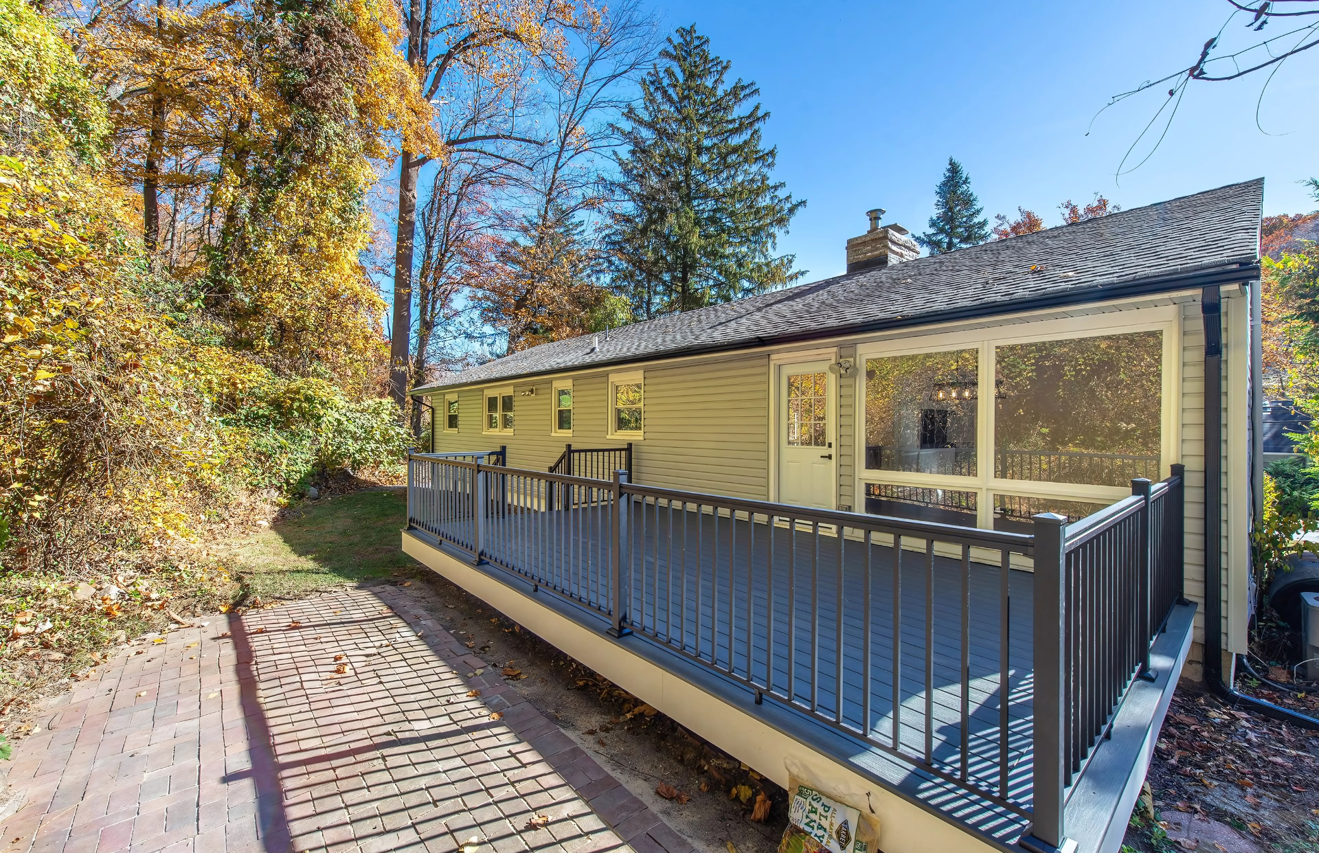A yellow house with a large deck surrounded by trees.