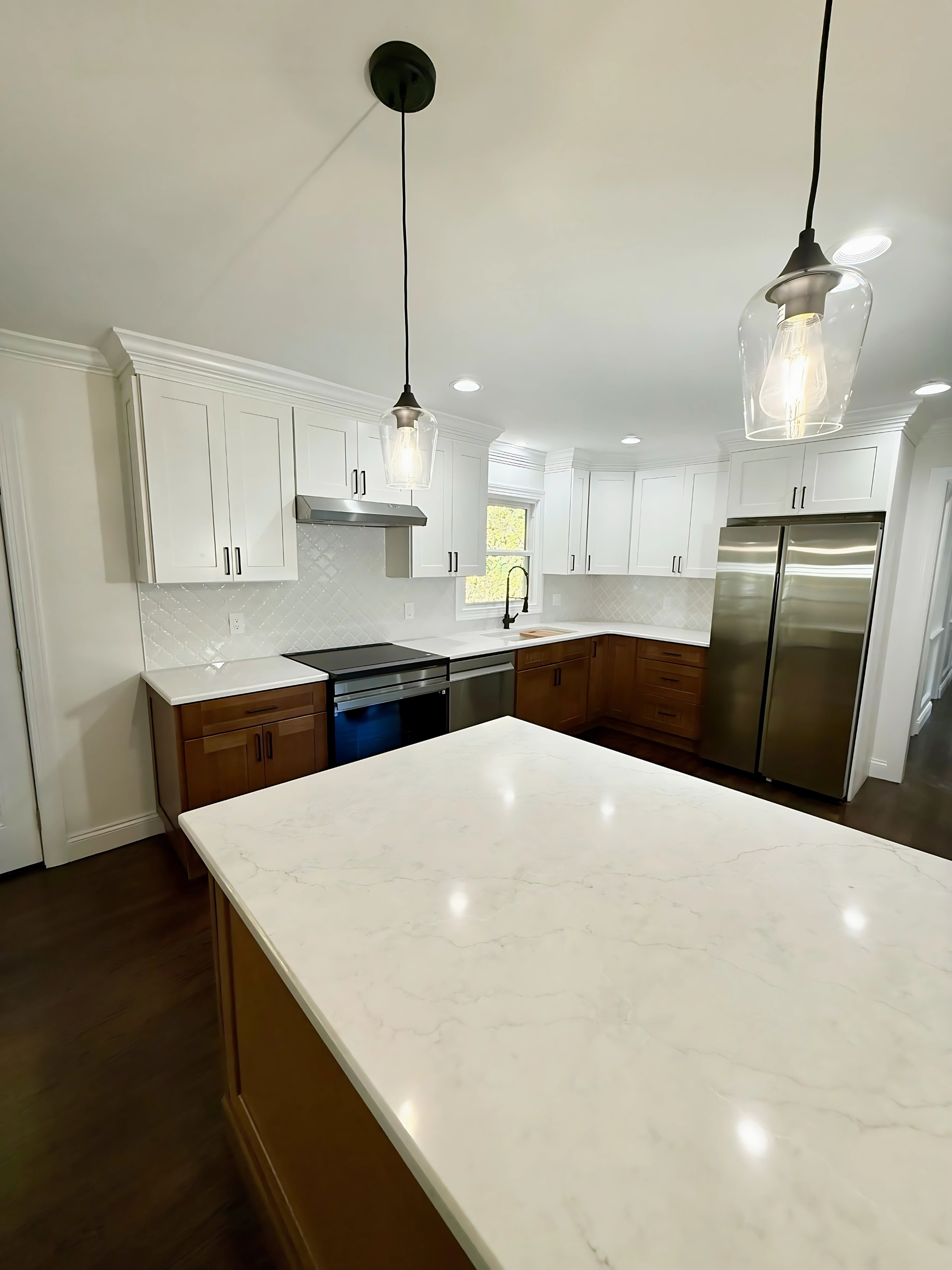 A kitchen with white cabinets , stainless steel appliances , and a large island.