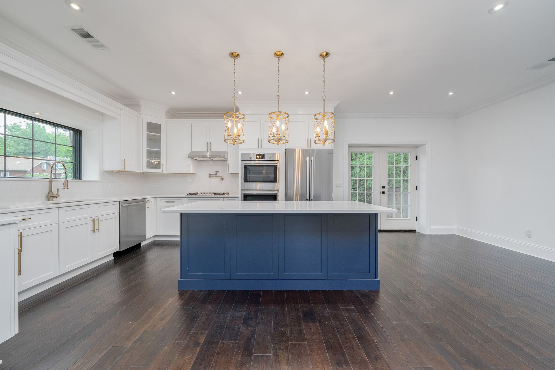 An empty kitchen with a blue island and white cabinets.