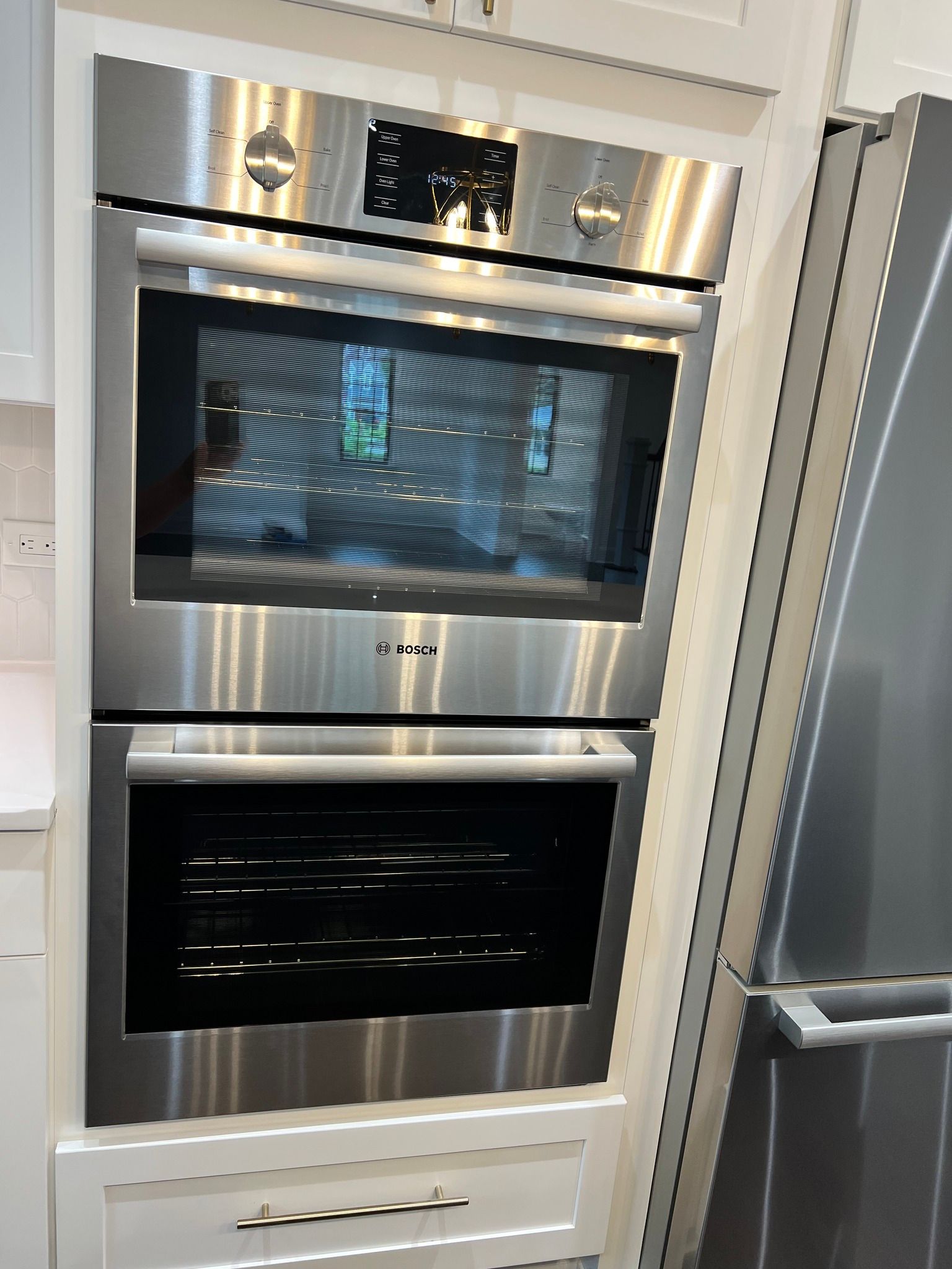 A stainless steel oven is in a kitchen next to a refrigerator.