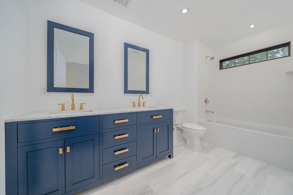 A bathroom with two sinks , two mirrors and a bathtub.