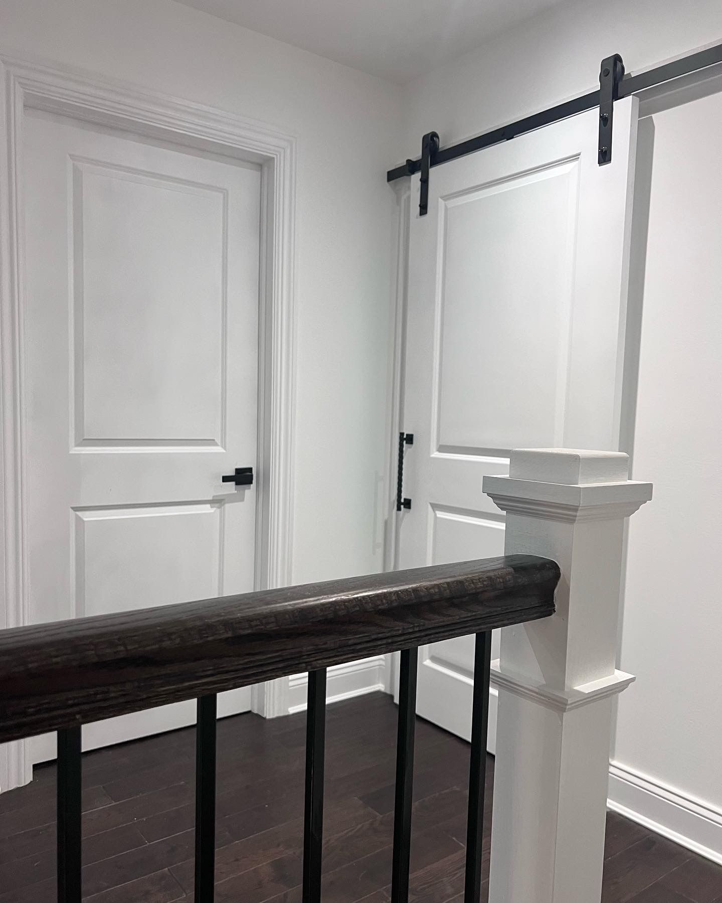 A staircase with a wooden railing and sliding barn doors.