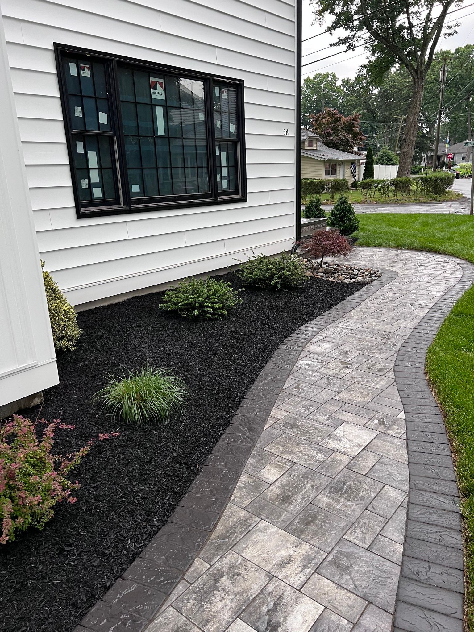 A walkway leading to a white house with a black window.