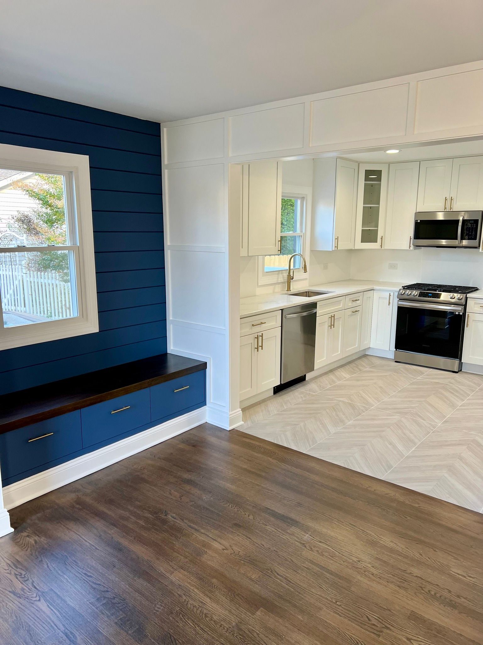 A kitchen with white cabinets and stainless steel appliances and a blue wall.