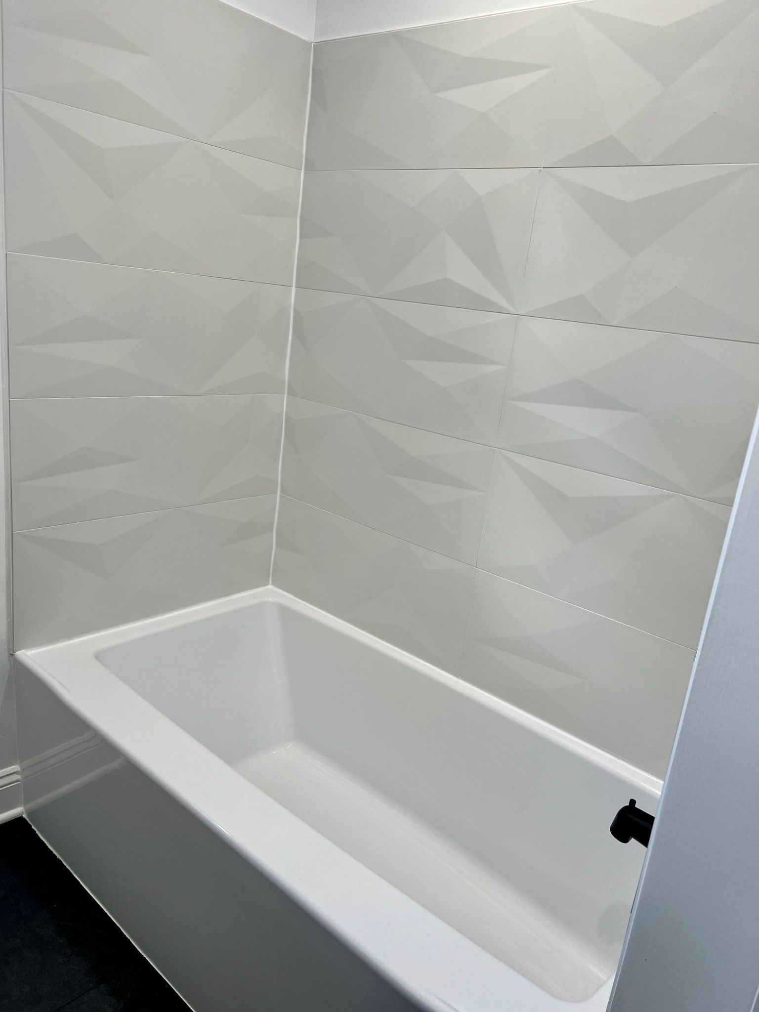 A bathtub in a bathroom with white tiles on the wall.