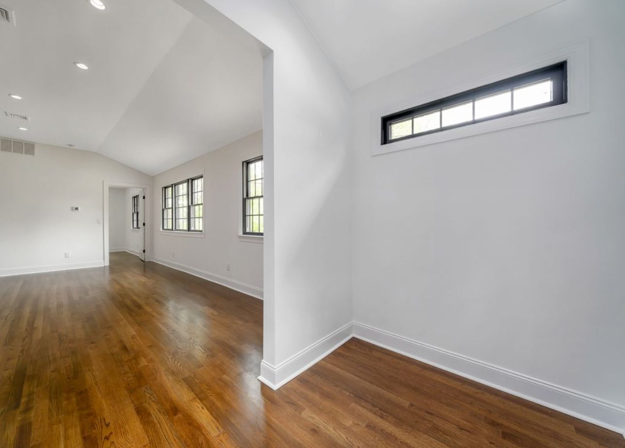 A large empty room with hardwood floors and white walls.