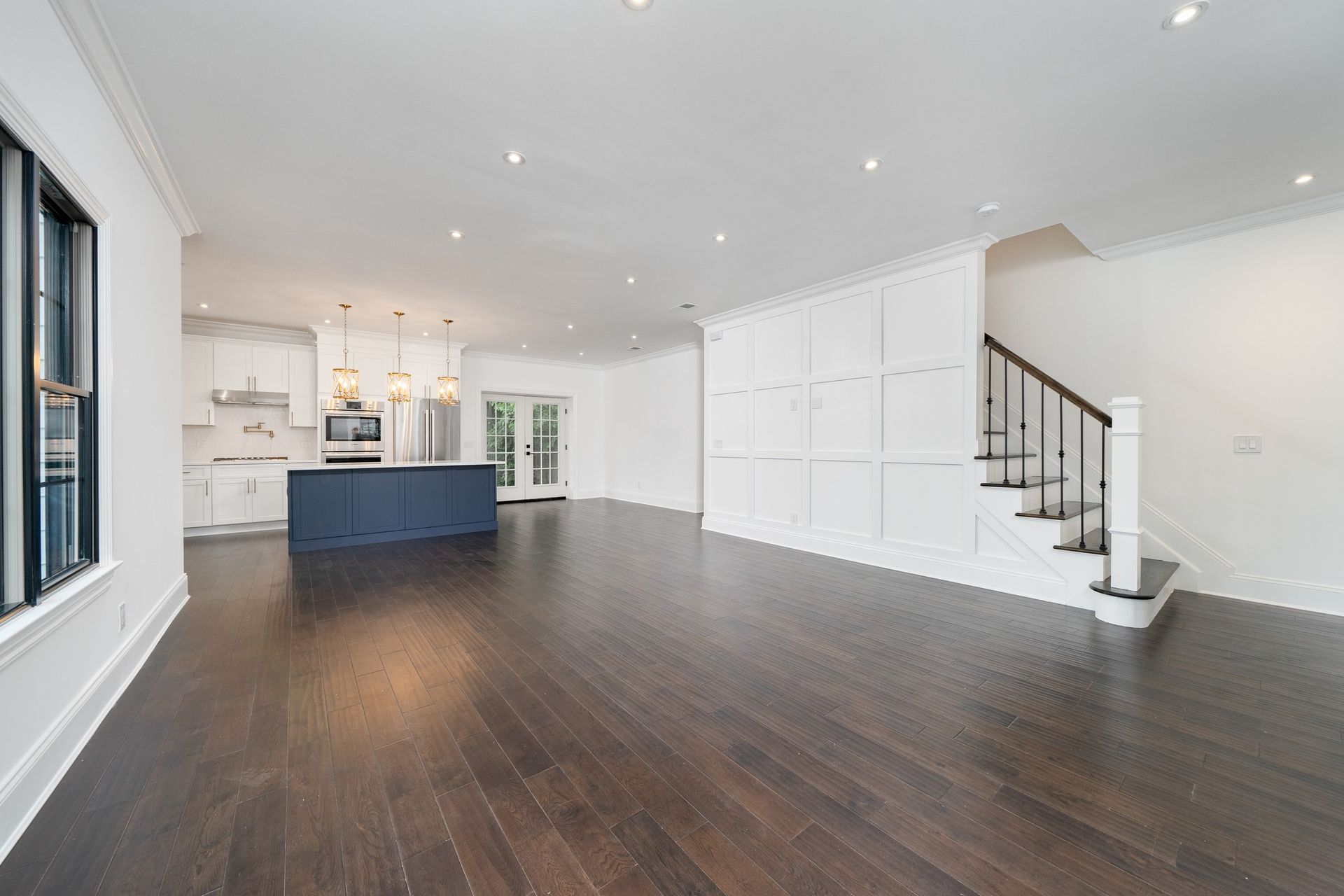 A large empty room with hardwood floors and stairs in a house.