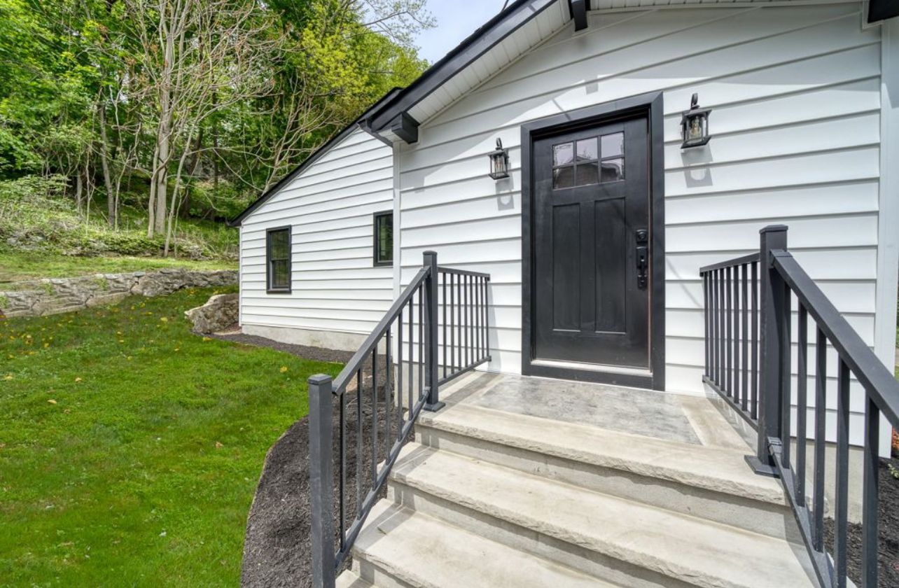 A white house with a black door and stairs leading to it.