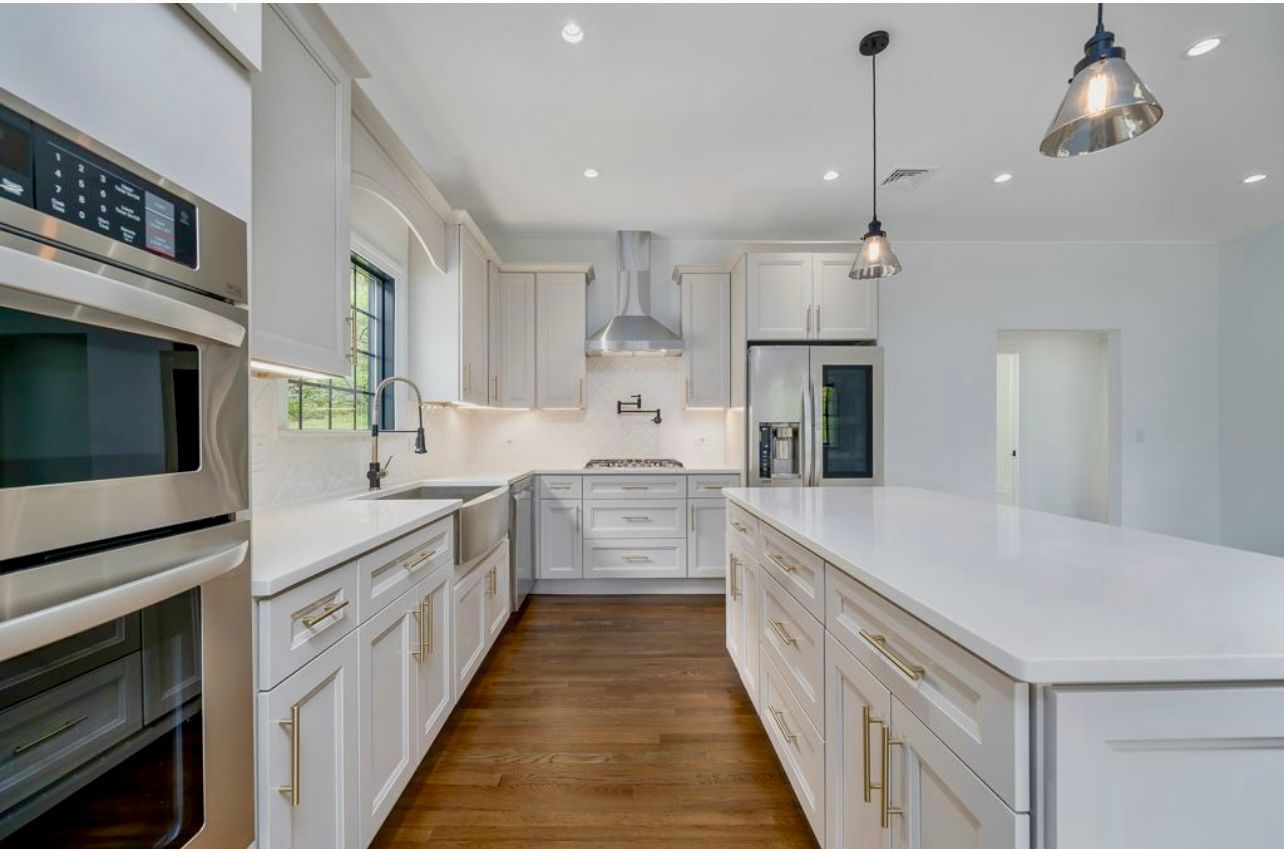 A kitchen with white cabinets , stainless steel appliances , and a large island.
