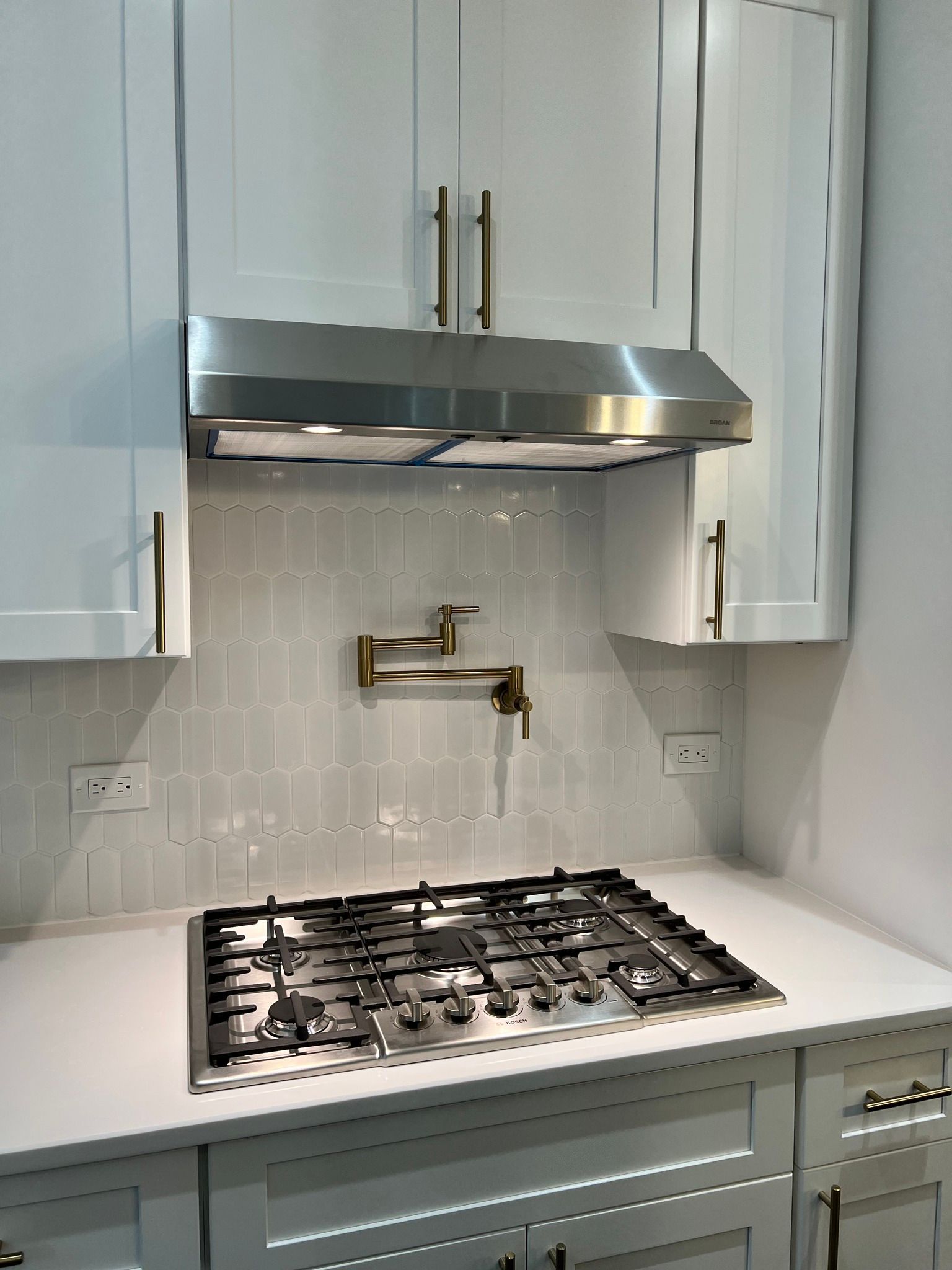 A kitchen with white cabinets and a stove top oven