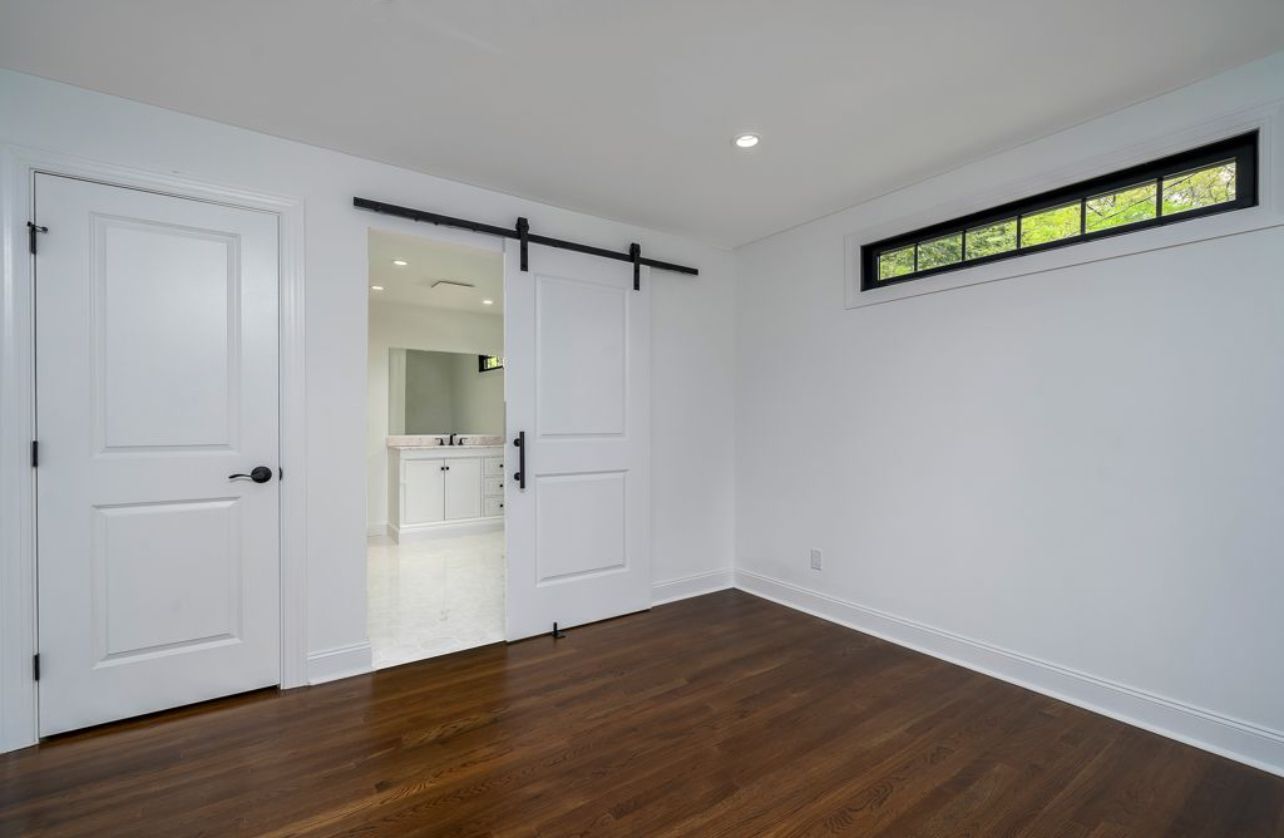 An empty room with a sliding barn door leading to a bathroom.