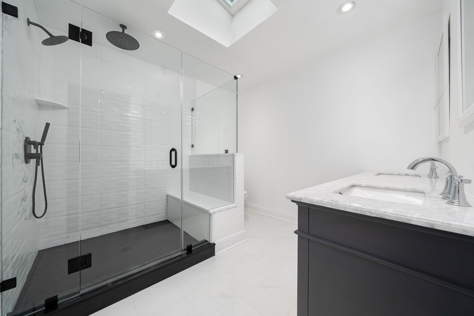 A bathroom with a walk in shower , sink , and skylight.