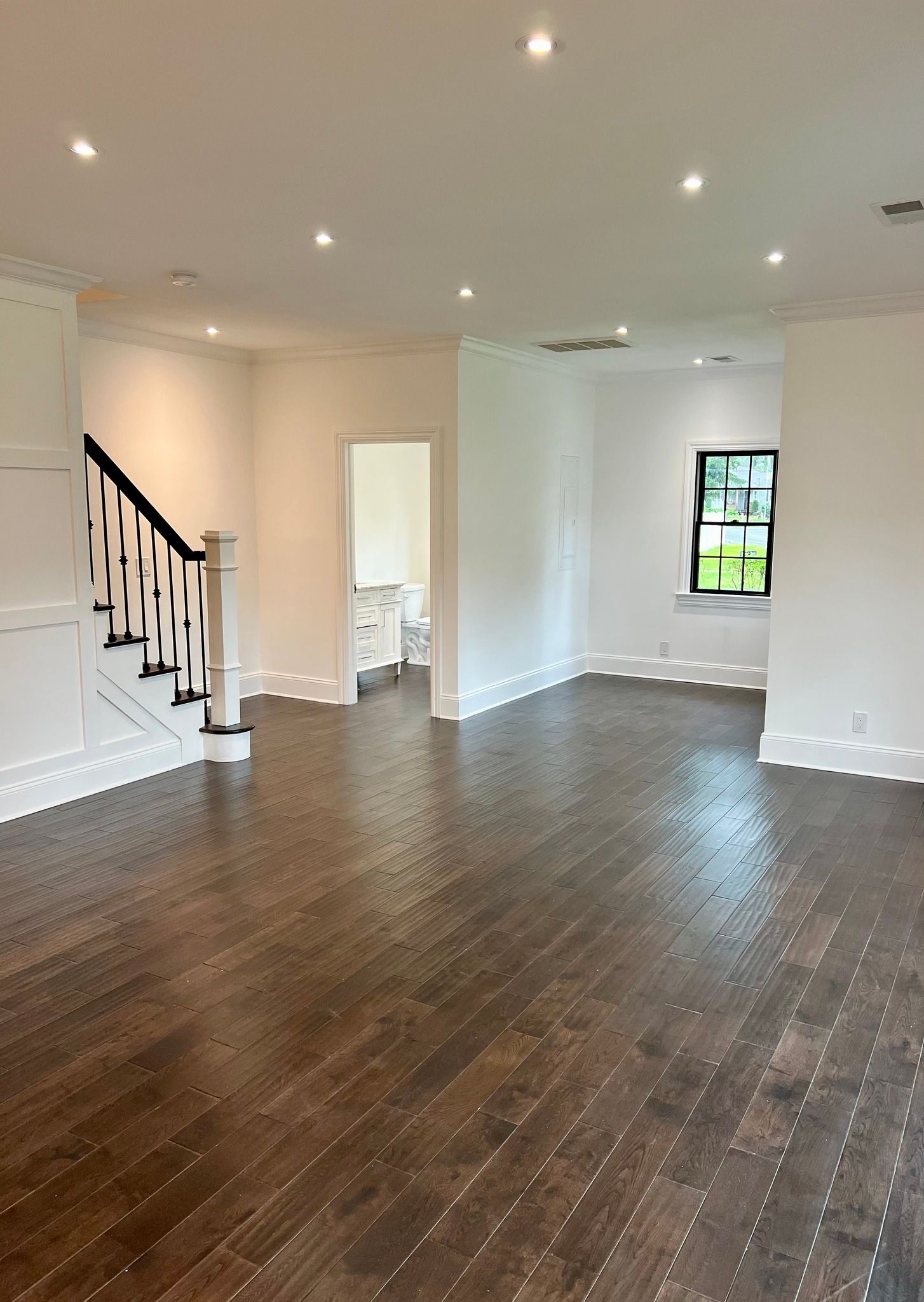 An empty living room with hardwood floors and stairs.